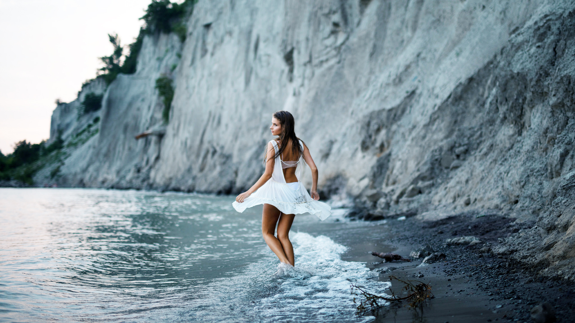 Девушка снимает купальник на скале у моря