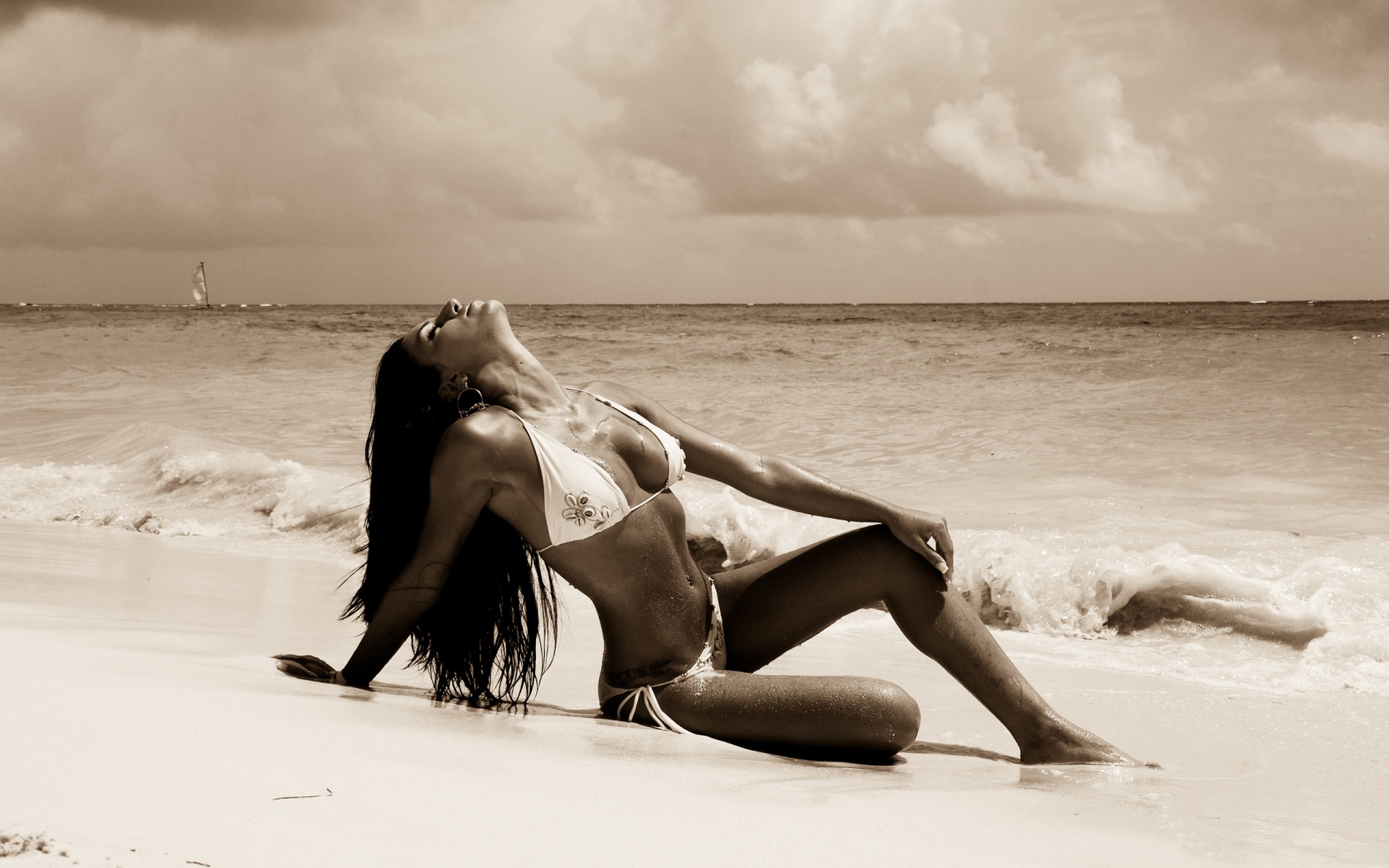 Красотка с длинными волосами эротично извивается вокруг шеста на пляже