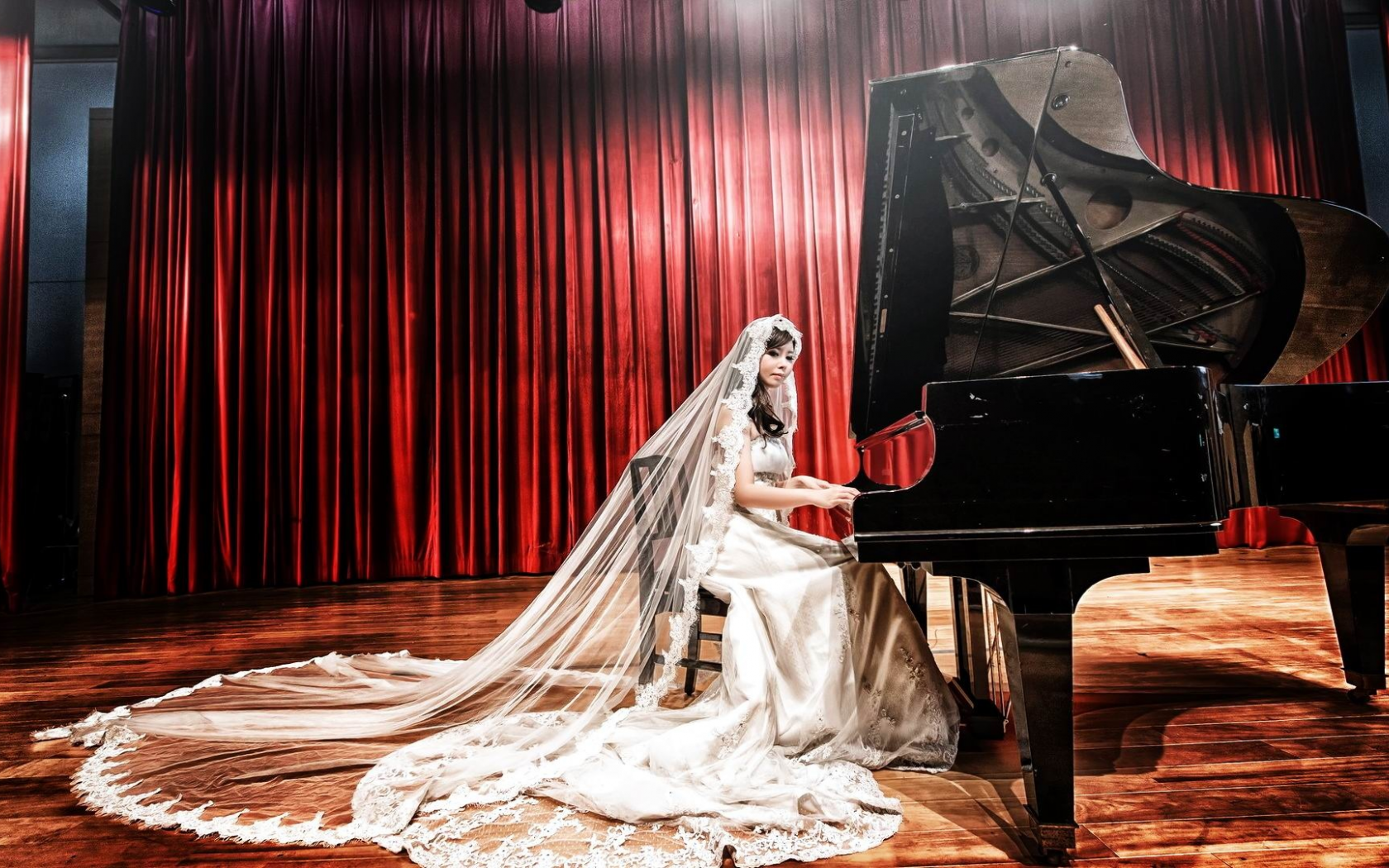 Высокая пианистка в прозрачной юбке возле белого рояля