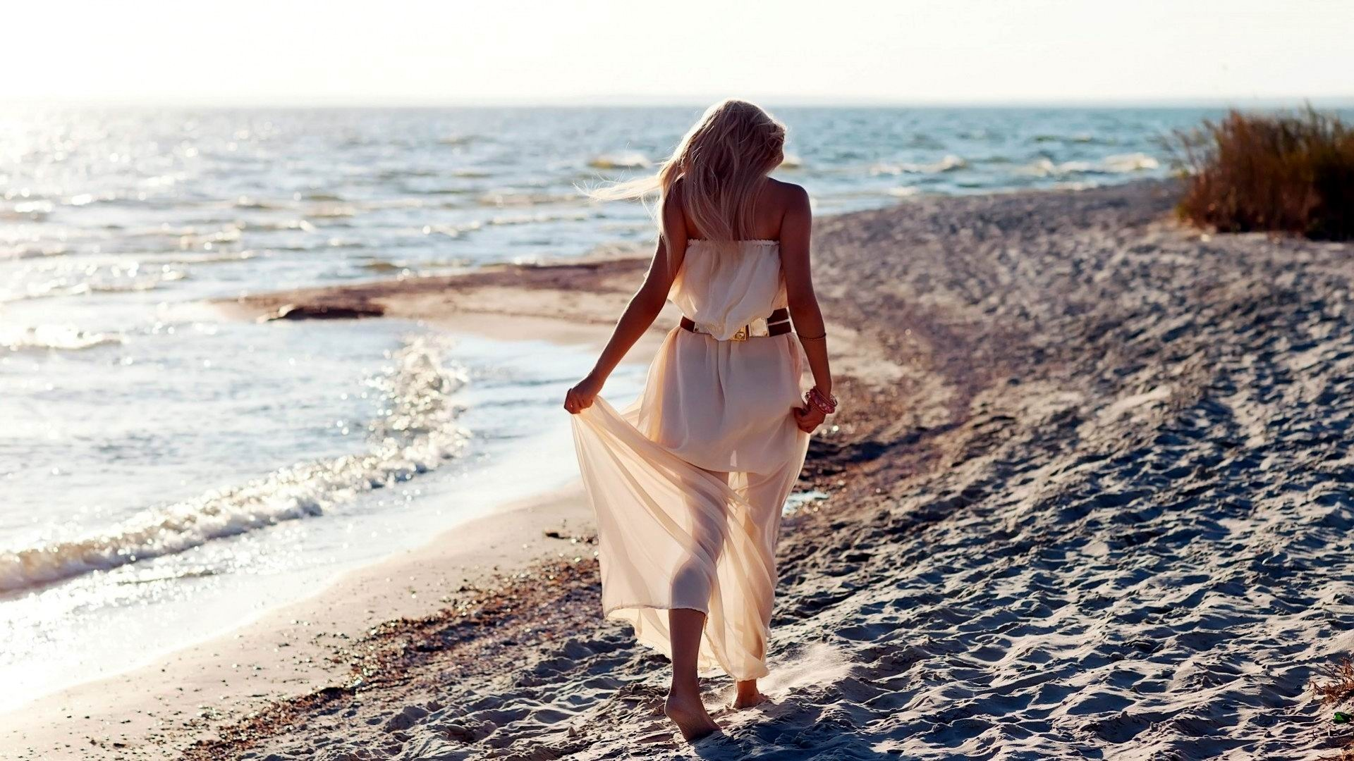 Молодая девушка снимает платье отдыхая на пляже