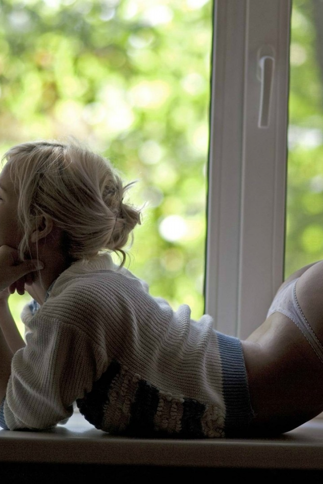 Сексуальная блондинка в желтых стрингах возле большого окна