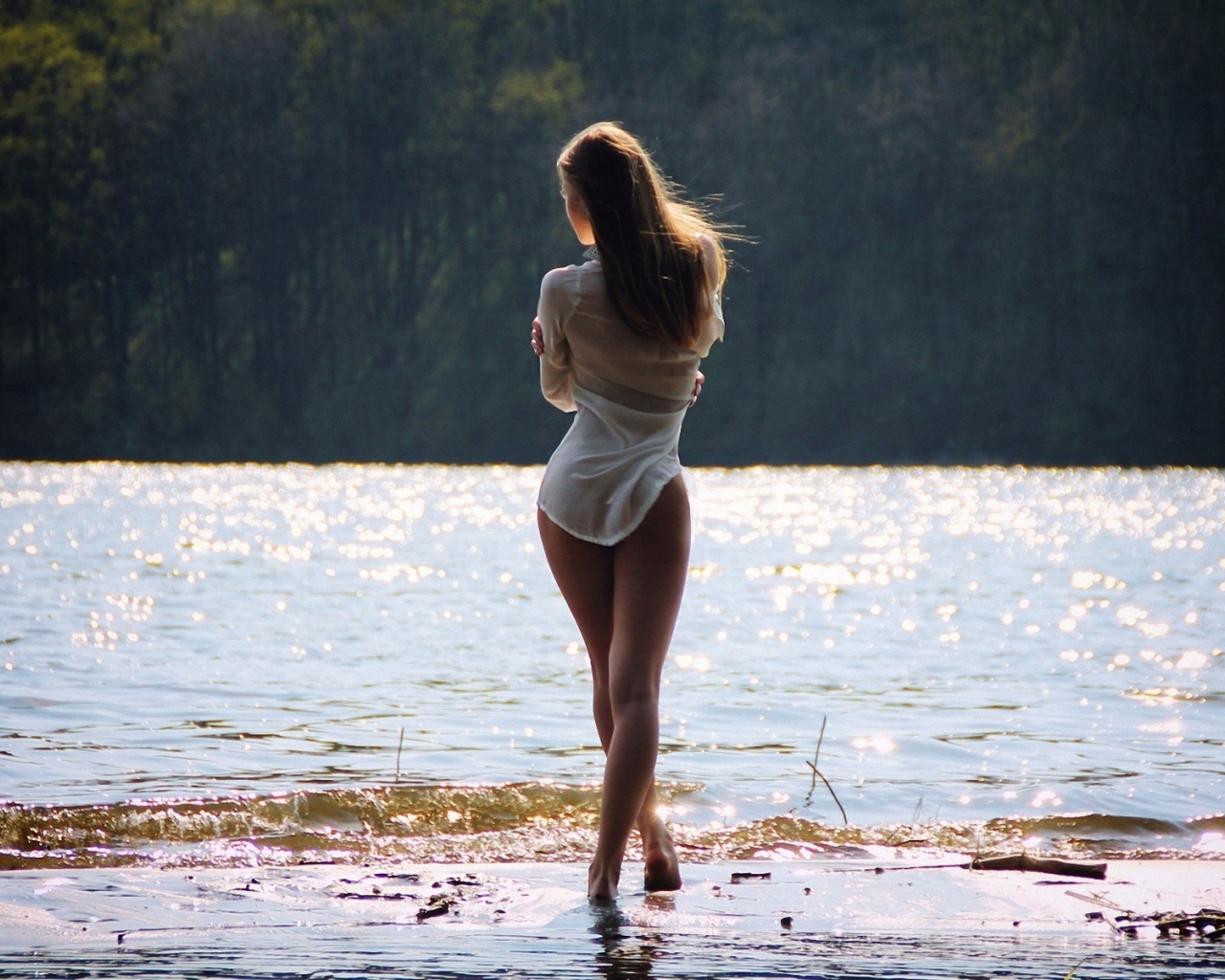 Привлекательная дама позирует голой на берегу реки